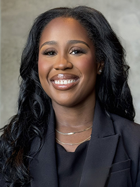 A woman in a black business suit smiles confidently.