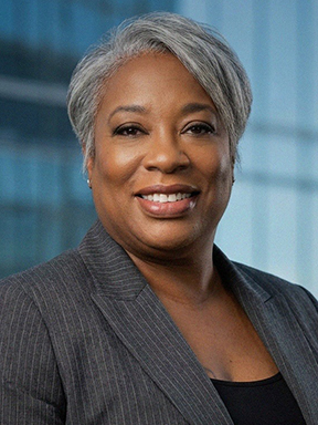A smiling woman with short gray hair in a dark gray business suit.