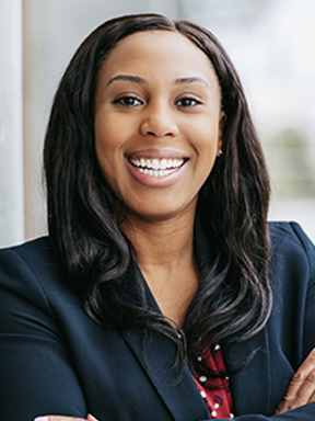 A young woman in a dark blazer smiling confidently.