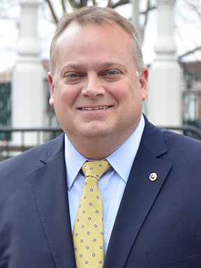 A man dressed in a blue suit and yellow necktie.