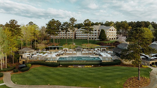 A picturesque resort enveloped by verdant trees and grassy landscapes, creating a peaceful retreat in the outdoors.