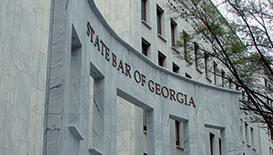 The words State Bar of Georgia appear on a gray marble building while tree branches with green leaves can be seen to the right.
